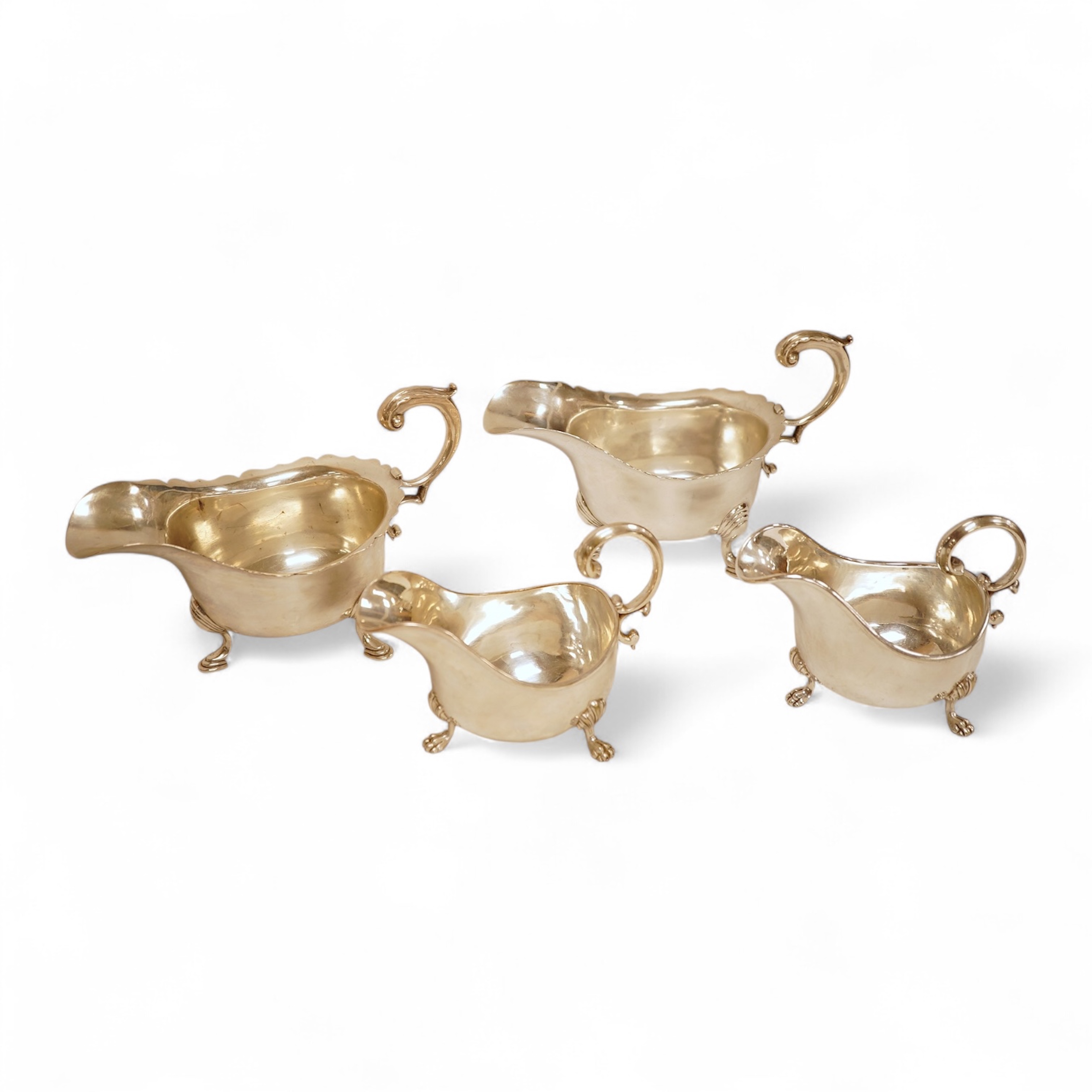 A pair of George V silver sauceboats, with cut borders and flying scroll handles, on three hoof feet, by J.B. Chatterley & Co Ltd, Birmingham, 1928, length 19.3cm, 19.3oz, together with a pair of silver plated Elkington